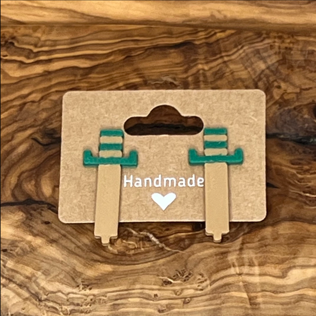 Pair of earrings on a 'Handmade' card against a wooden background