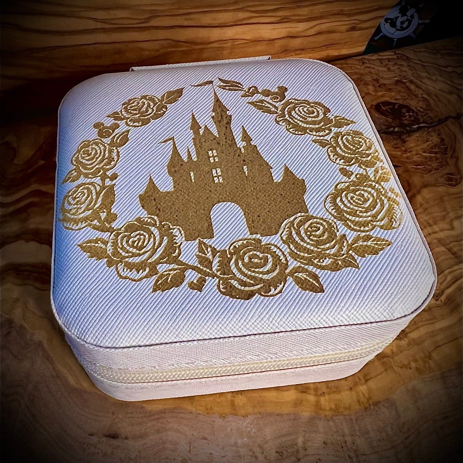 White jewelry box with gold castle and rose design on a wooden surface