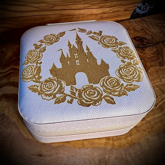 White jewelry box with gold castle and rose design on a wooden surface