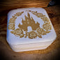 White jewelry box with gold castle and rose design on a wooden surface