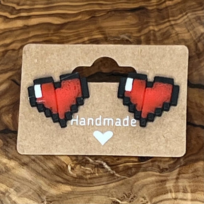 Pixel heart-shaped earrings on a 'Handmade' card against a wooden background