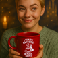 Person holding a red mug with text against a warm, blurred background