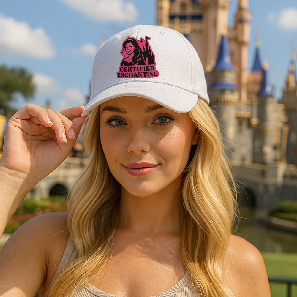 Woman wearing a white cap with 'Certified Enchanting' text in front of a castle.
