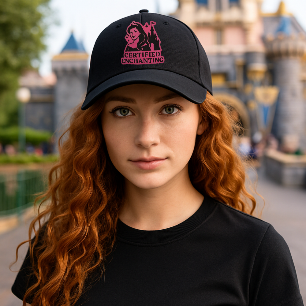 Person wearing a black cap with pink text in front of a castle-like structure