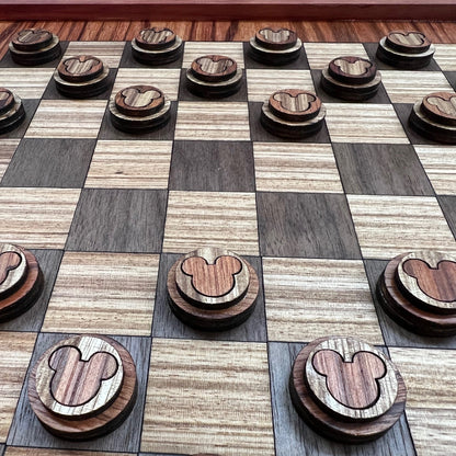 A luxury handcrafted checkerboard made from exotic woods with a pattern of squares in shades of walnut, cherry, redwood, and zebrawood, accompanied by matching round game pieces.