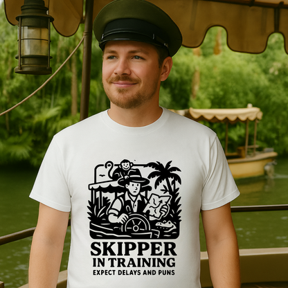Man wearing a white t-shirt with a 'Skipper in Training' graphic and text, standing on a boat.